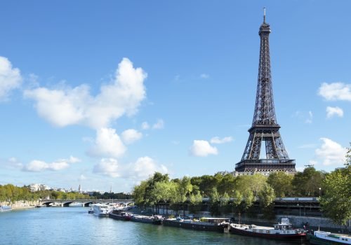 Eiffel Tower landscape taken from the south side, with River Seine, boats and blue sky with copyspace..