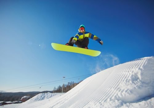 Portrait of young man snowboarding in winter against blue sky